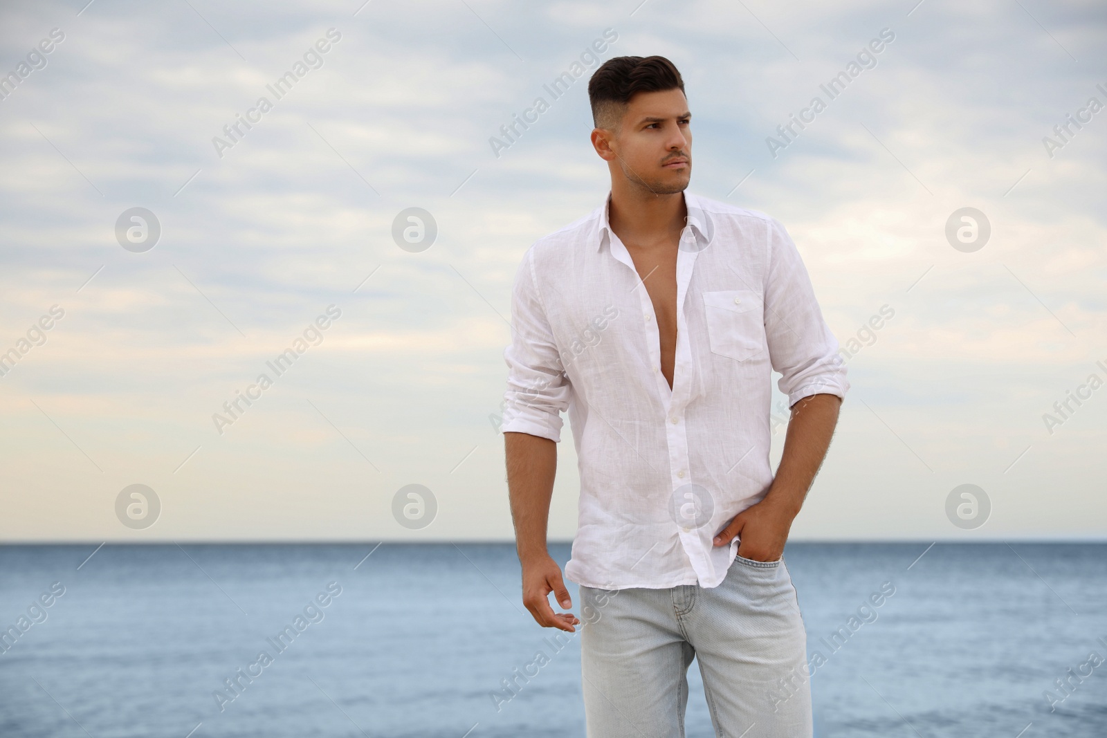 Photo of Handsome man on beach near sea. Space for text