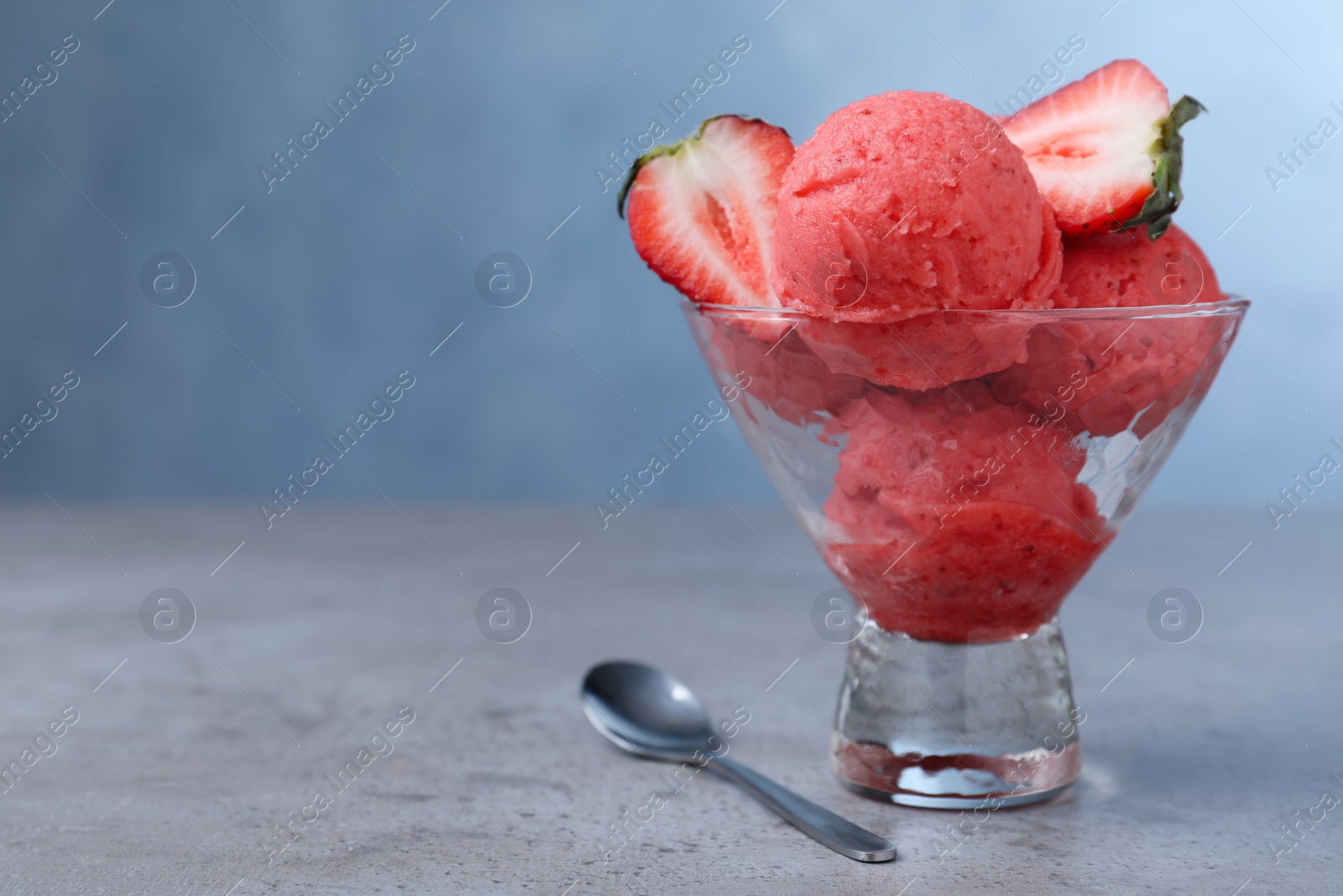 Photo of Delicious strawberry ice cream served on grey table. Space for text