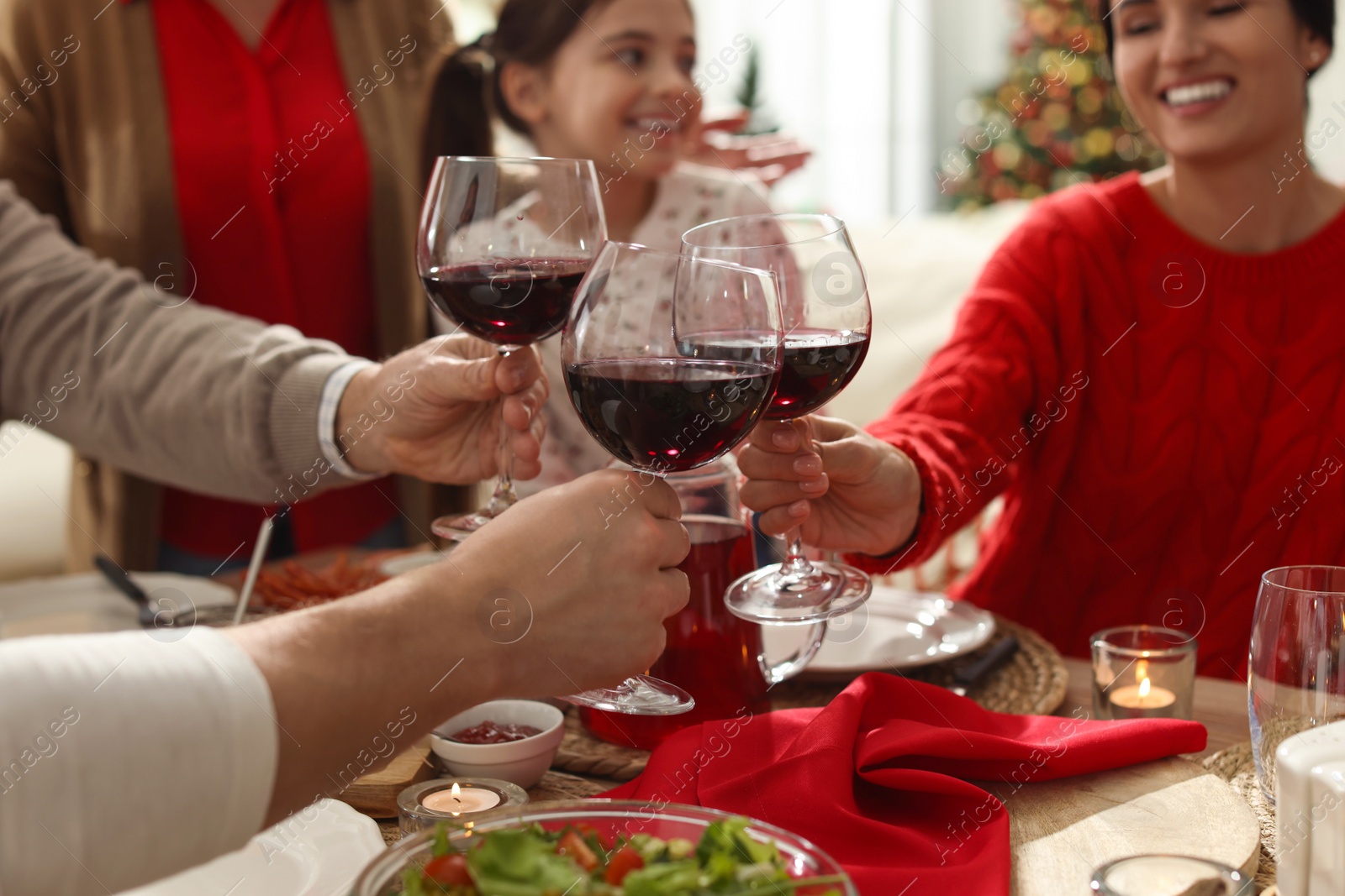 Photo of Family clinking glasses of wine at festive dinner, focus on hands. Christmas celebration