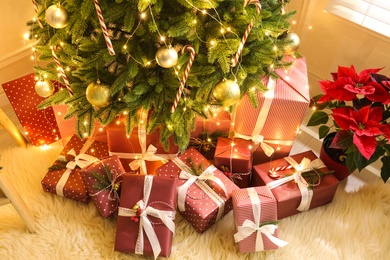 Many different gifts under Christmas tree indoors, above view