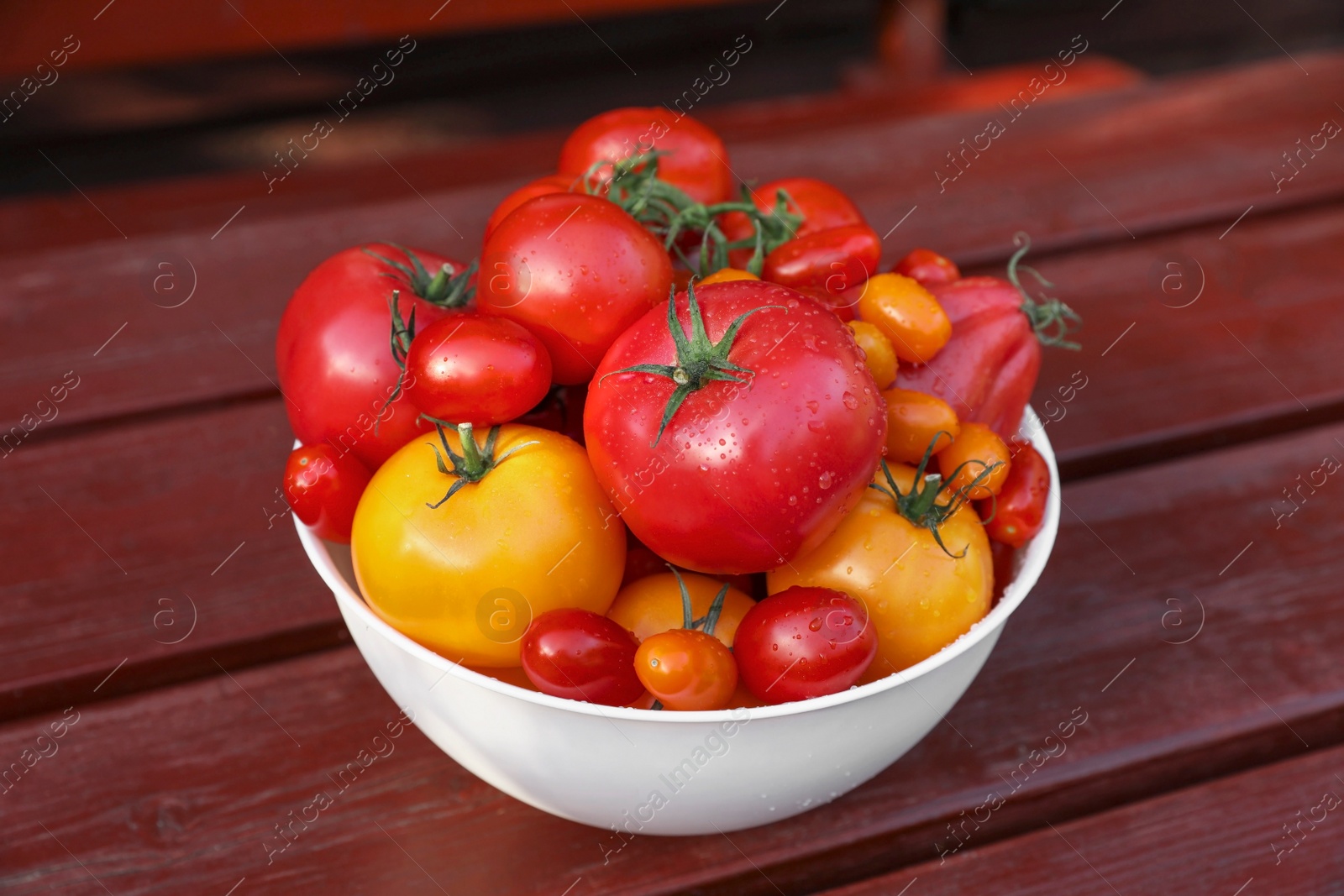 Photo of Bowl with fresh tomatoes on wooden table