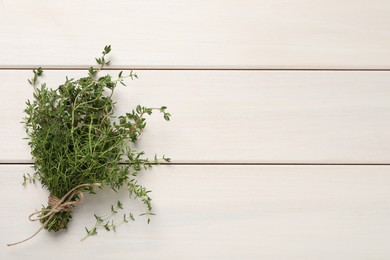 Photo of Bunch of aromatic thyme on white wooden table, top view. Space for text