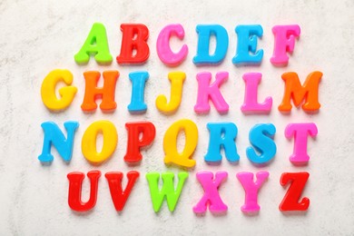 Photo of Colorful magnetic letters on white textured background, flat lay. Alphabetical order