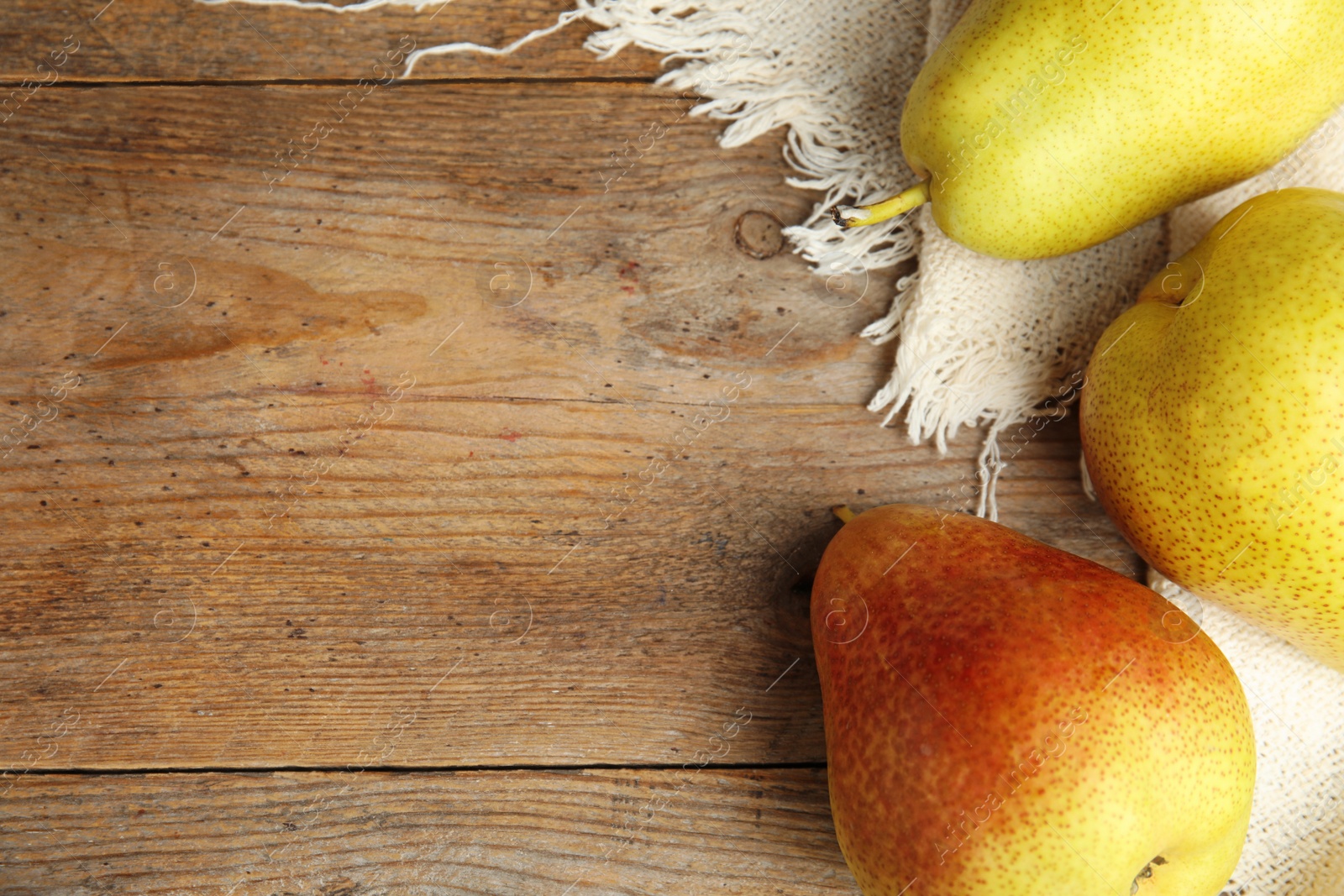 Photo of Ripe juicy pears on brown wooden table, flat lay. Space for text