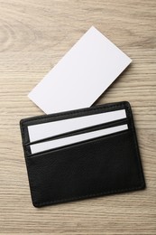 Leather business card holder with blank cards on wooden table, top view