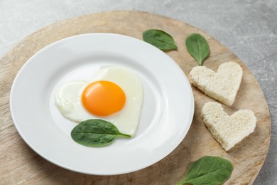 Photo of Romantic breakfast with heart shaped fried egg and toasts on light grey table, closeup
