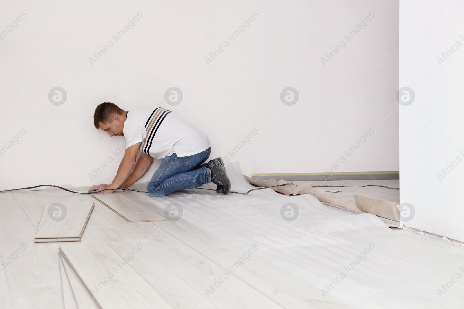 Photo of Man installing new laminate flooring in room