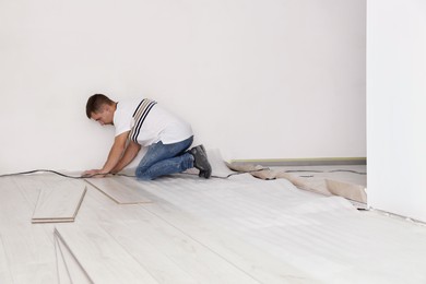 Man installing new laminate flooring in room