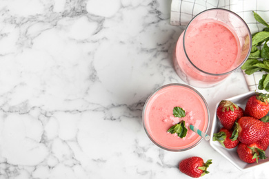 Photo of Tasty strawberry smoothies with mint in glasses on white marble table, flat lay. Space for text