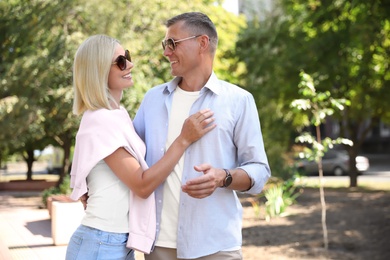 Happy couple walking along park on summer day