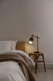 Photo of Stylish lamp on table near bed indoors