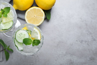 Refreshing water with cucumber, lemon and mint on grey table, flat lay. Space for text