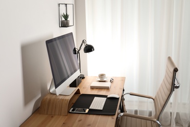 Stylish workplace interior with modern computer on table. Mockup for design