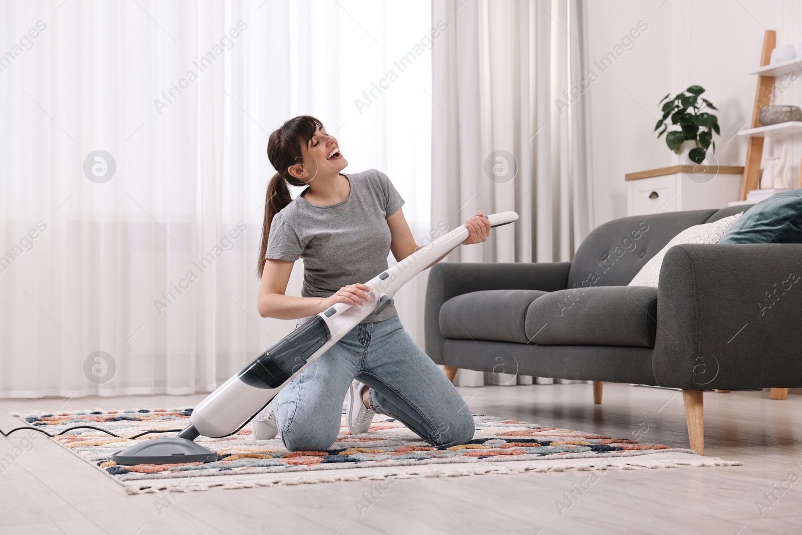 Photo of Happy young housewife having fun while cleaning at home