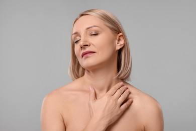 Photo of Beautiful woman touching her neck on grey background
