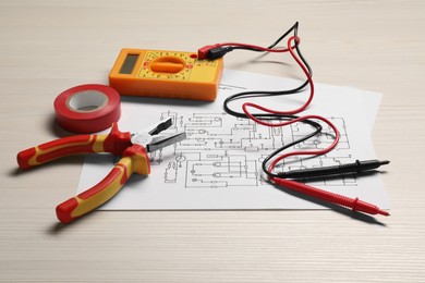 Wiring diagrams, digital multimeter and tools on white wooden table, closeup