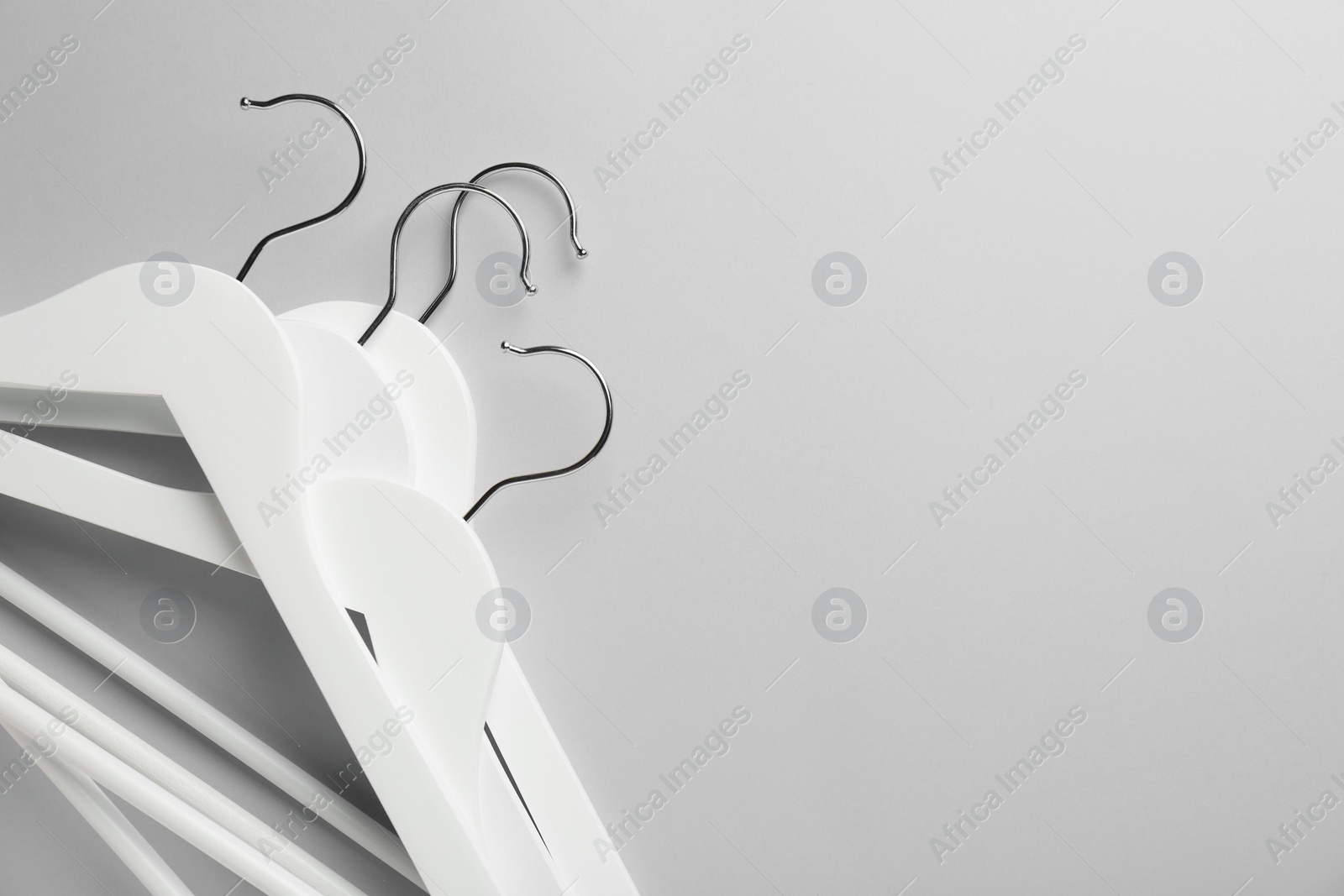 Photo of White hangers on light gray background, top view. Space for text