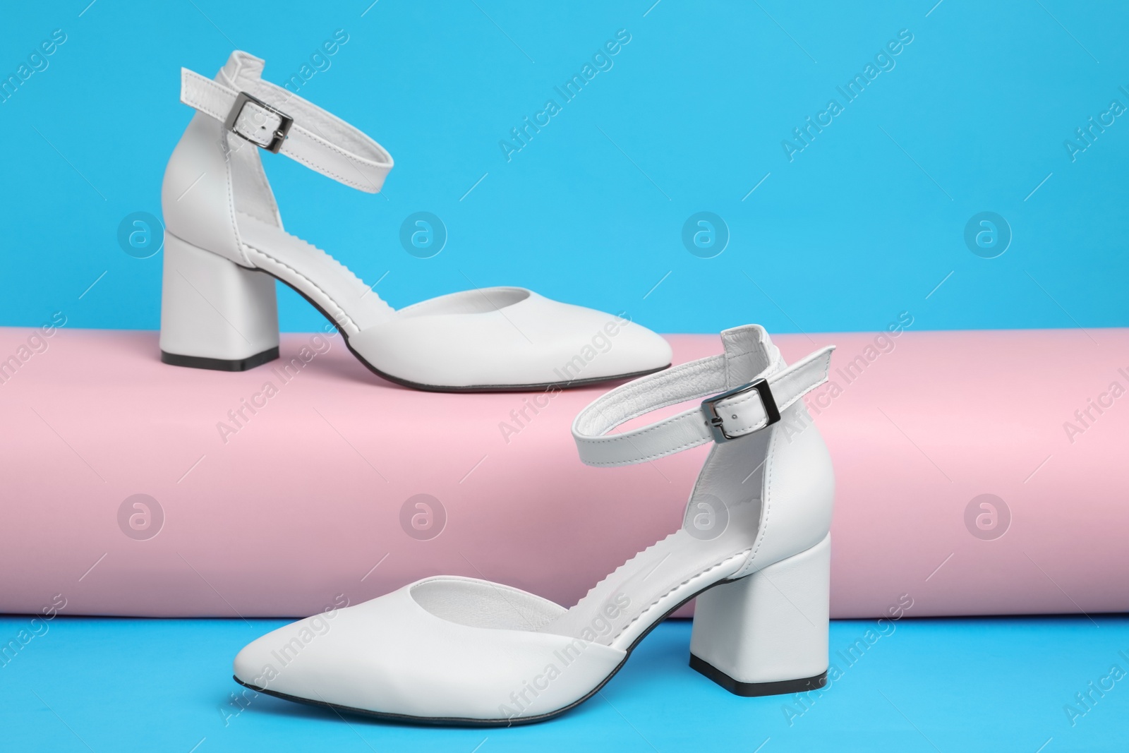 Photo of Stylish white female shoes on light blue background