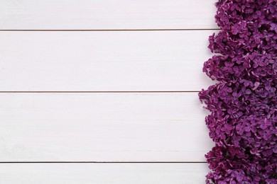 Photo of Beautiful lilac flowers on white wooden background, top view with space for text