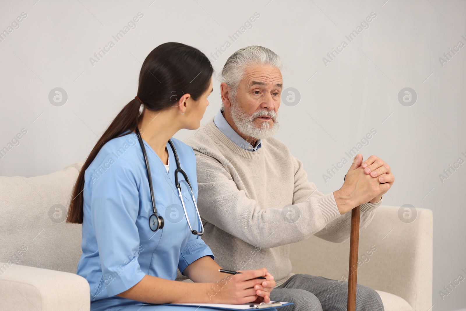 Photo of Nurse with clipboard listening to elderly patient in hospital