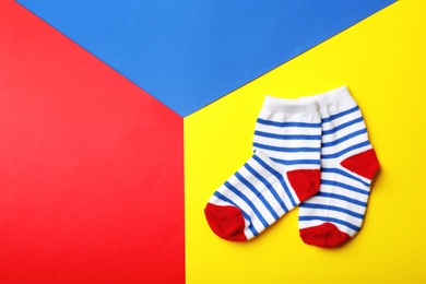 Photo of Pair of cute child socks and space for text on color background, top view