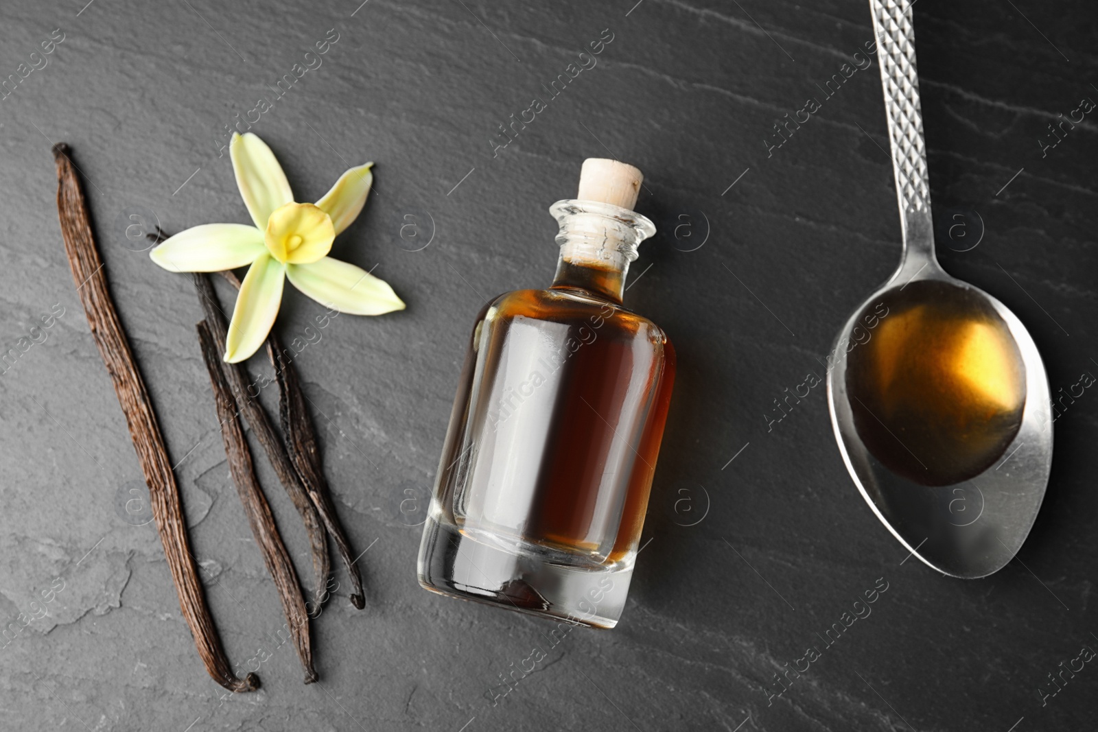 Photo of Flat lay composition with vanilla extract on black table