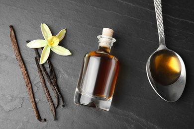 Photo of Flat lay composition with vanilla extract on black table