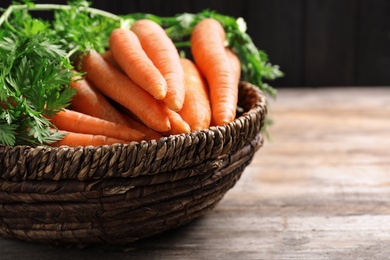 Photo of Basket of carrots on wooden table, closeup