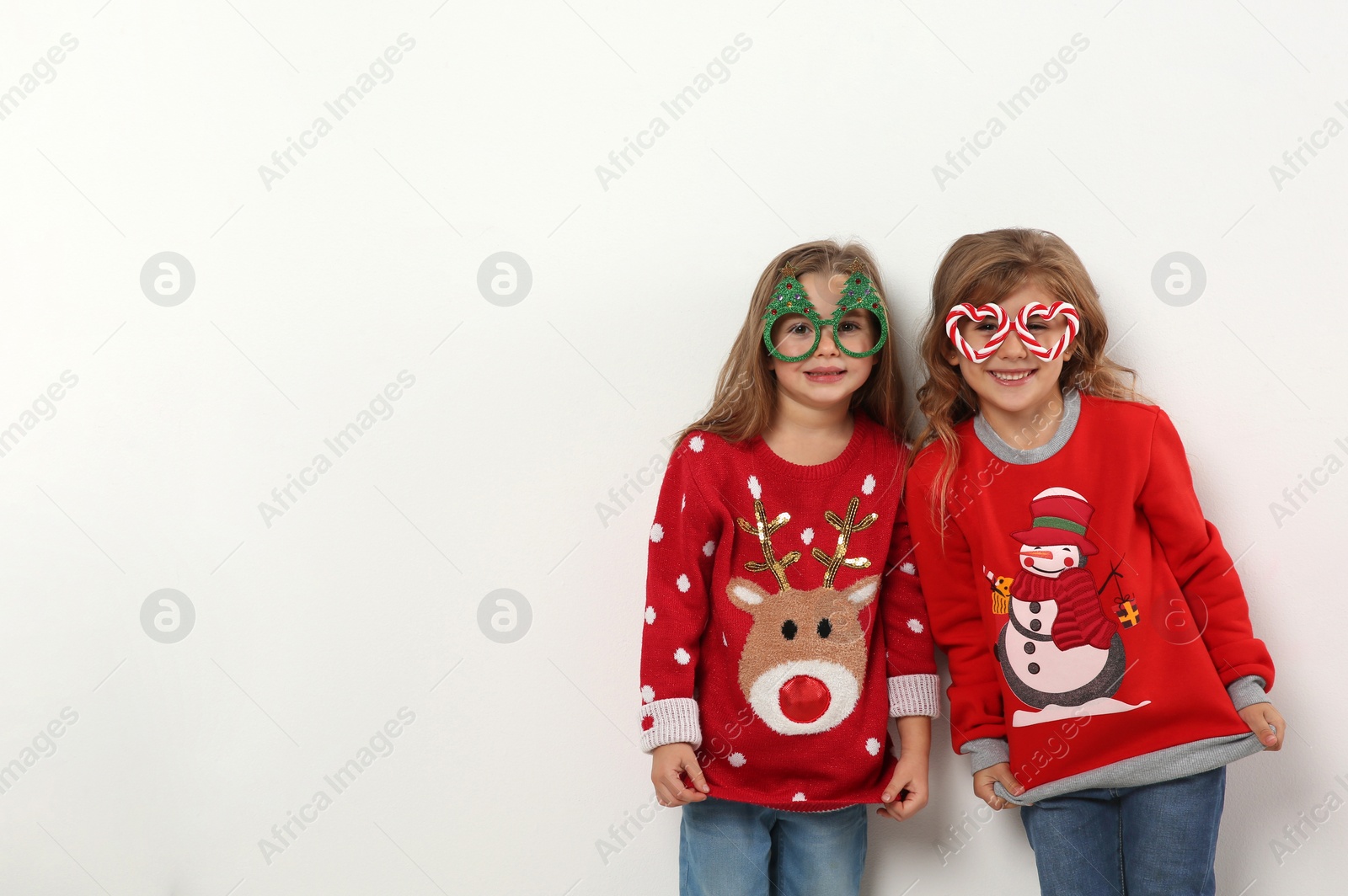 Photo of Kids in Christmas sweaters and festive glasses on white background