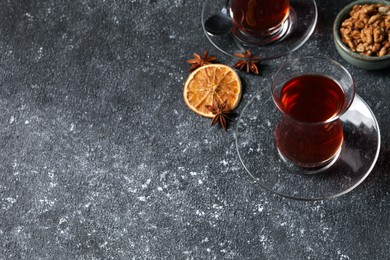 Photo of Glasses of traditional Turkish tea and ingredients on grey textured table. Space for text