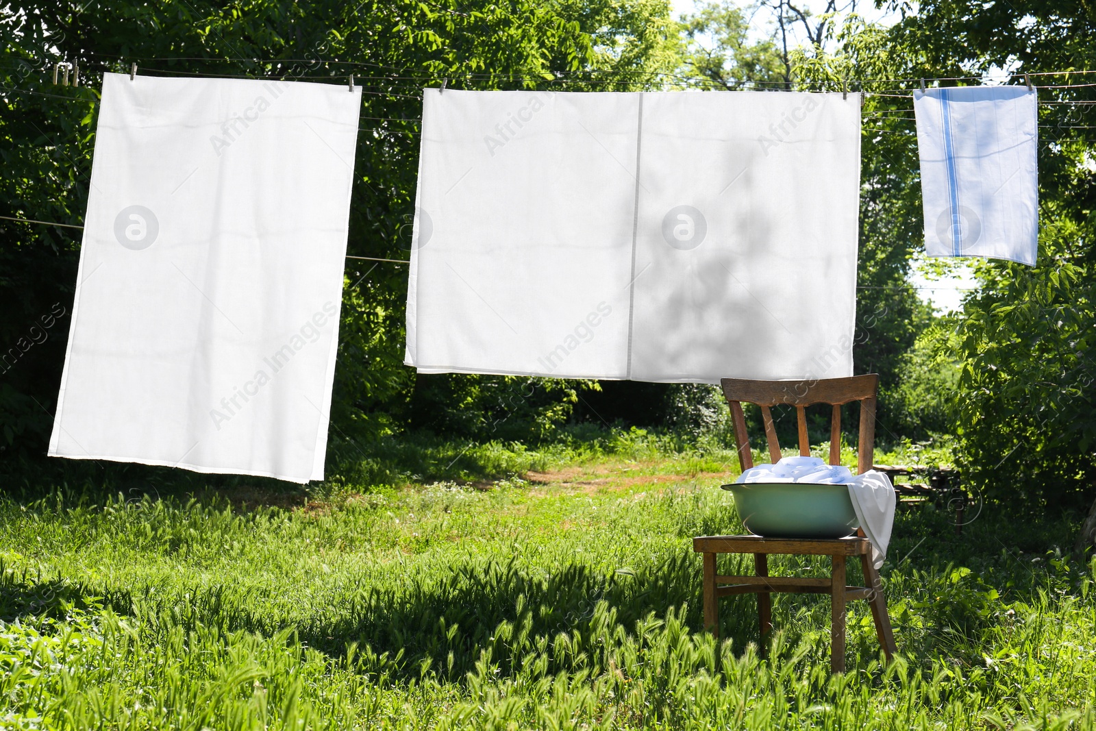 Photo of Washing line with clean laundry and clothespins outdoors