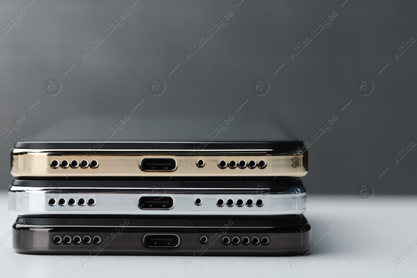 Photo of Stack of modern smartphones on white table, closeup. Space for text