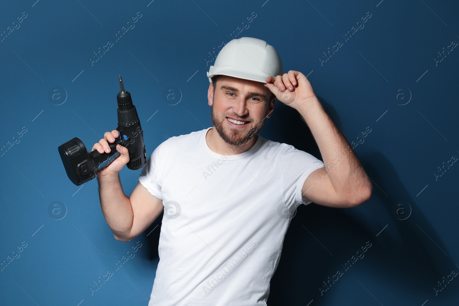 Photo of Young working man with electric screwdriver on color background