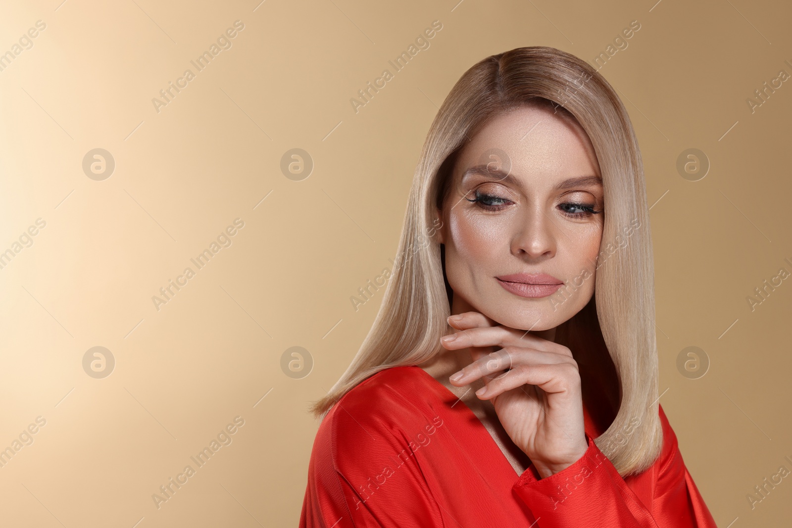 Image of Portrait of stylish attractive woman with blonde hair on dark beige background, space for text