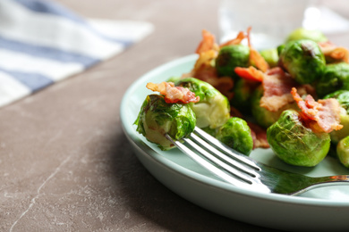 Photo of Delicious Brussels sprouts with bacon on marble table, closeup
