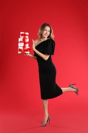 Beautiful young woman with Christmas presents on red background