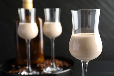 Photo of Coffee cream liqueur in glasses, bottle and beans on table, closeup
