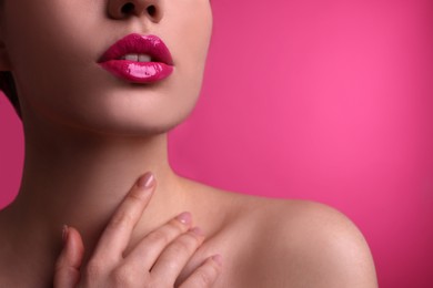 Closeup view of woman with beautiful full lips on pink background, space for text