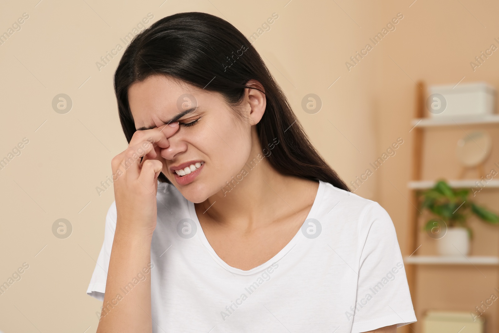 Photo of Young woman suffering from headache indoors. Hormonal disorders