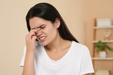 Photo of Young woman suffering from headache indoors. Hormonal disorders