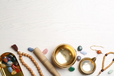 Photo of Flat lay composition with golden singing bowl on white wooden table, space for text. Sound healing
