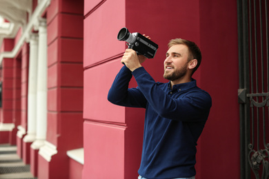 Young man with vintage video camera outdoors