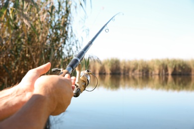 Man fishing alone at riverside on sunny day, closeup