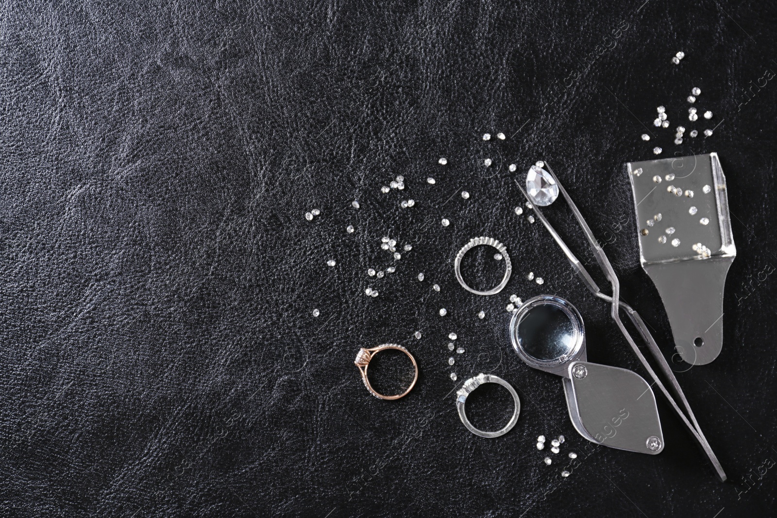 Photo of Flat lay composition with precious stones and jewelry tools on black leather background, space for text