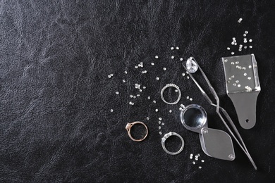 Photo of Flat lay composition with precious stones and jewelry tools on black leather background, space for text