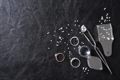 Flat lay composition with precious stones and jewelry tools on black leather background, space for text