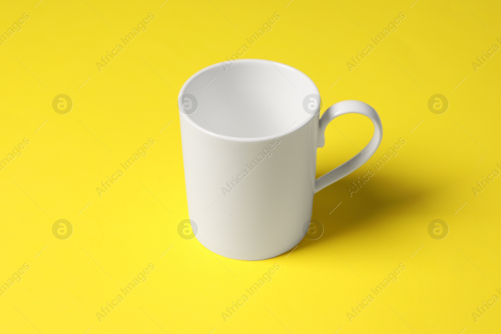 One white ceramic mug on yellow background Photo of One white ceramic mug on yellow background