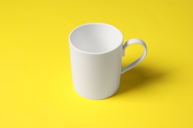 Photo of One white ceramic mug on yellow background