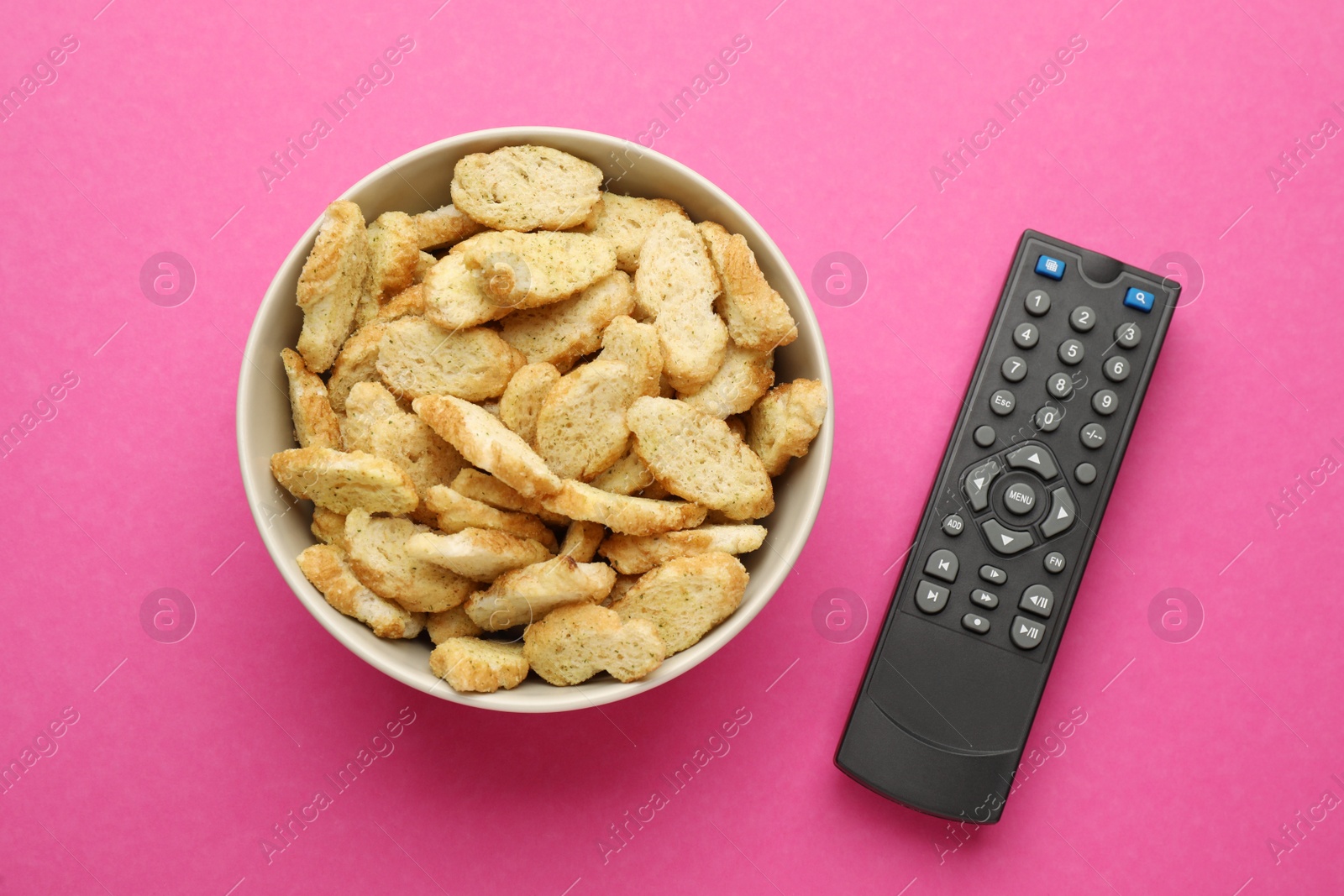 Photo of Remote control and rusks on pink background, flat lay