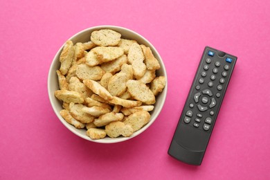 Photo of Remote control and rusks on pink background, flat lay